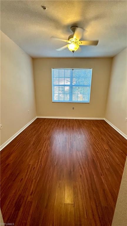 Spare room featuring dark wood-style flooring, a textured ceiling, and a ceiling fan