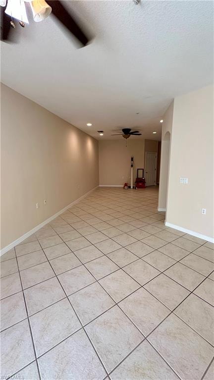 Empty room featuring a ceiling fan, recessed lighting, arched walkways, light tile patterned floors, and a textured ceiling