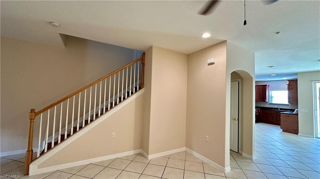 Staircase featuring arched walkways, tile patterned flooring, a ceiling fan, and recessed lighting