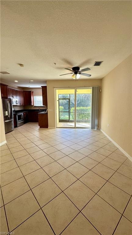 Unfurnished living room featuring a textured ceiling, healthy amount of natural light, ceiling fan, and light tile patterned floors