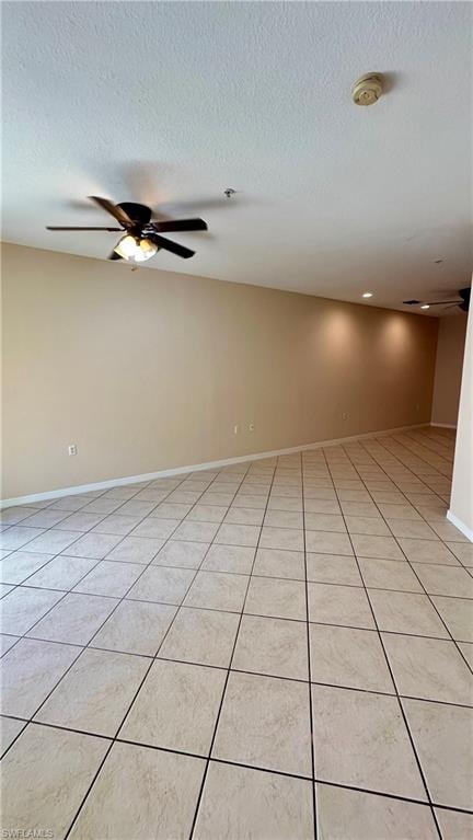Empty room with a ceiling fan, a textured ceiling, and light tile patterned flooring