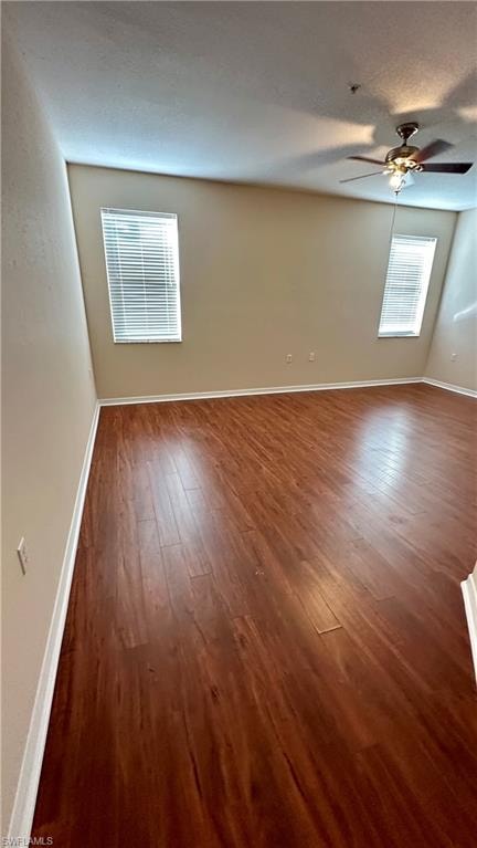 Spare room with dark wood-style floors and a ceiling fan