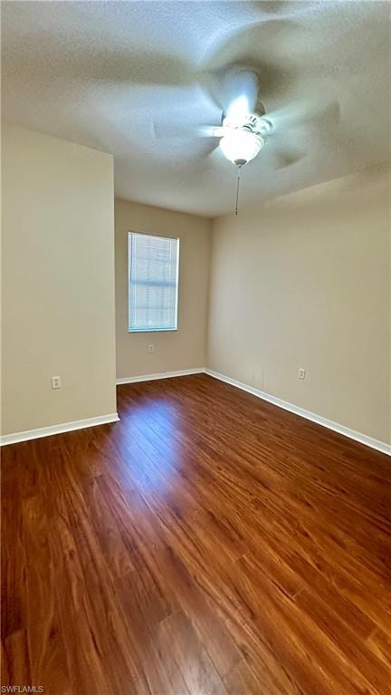 Spare room featuring a textured ceiling and dark wood-style floors