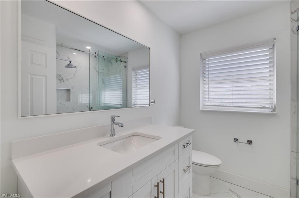 Full bathroom featuring light marble finish floors, a marble finish shower, vanity, and plenty of natural light