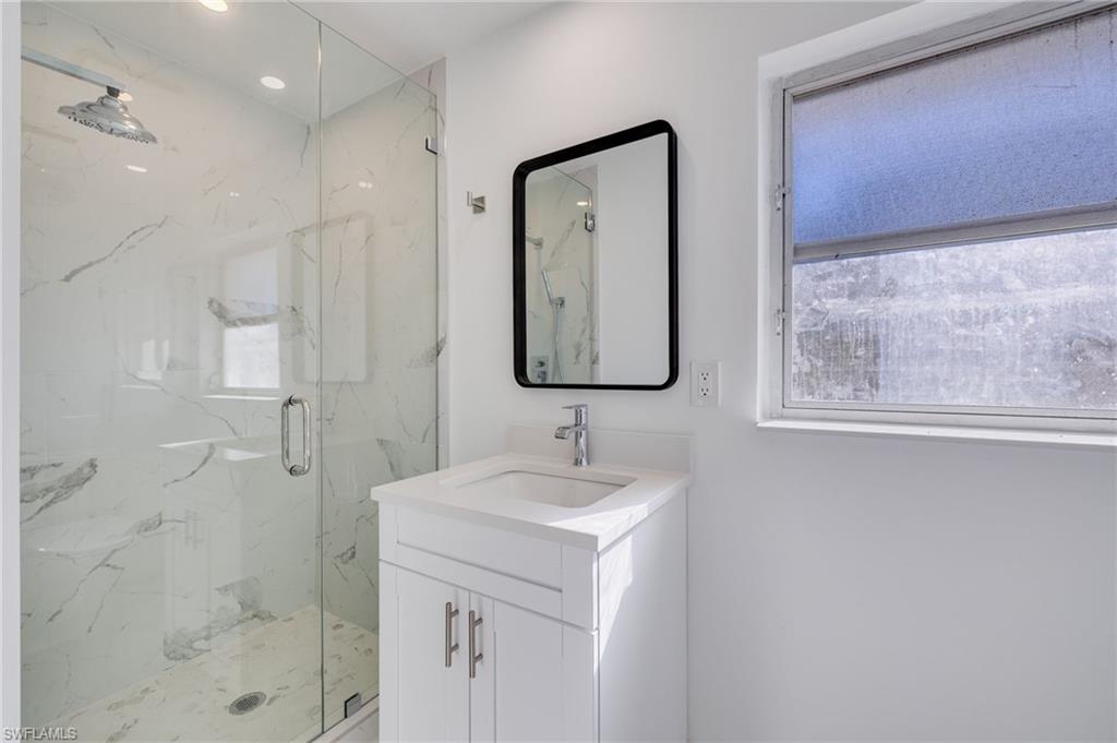 Bathroom featuring plenty of natural light, vanity, a marble finish shower, and recessed lighting