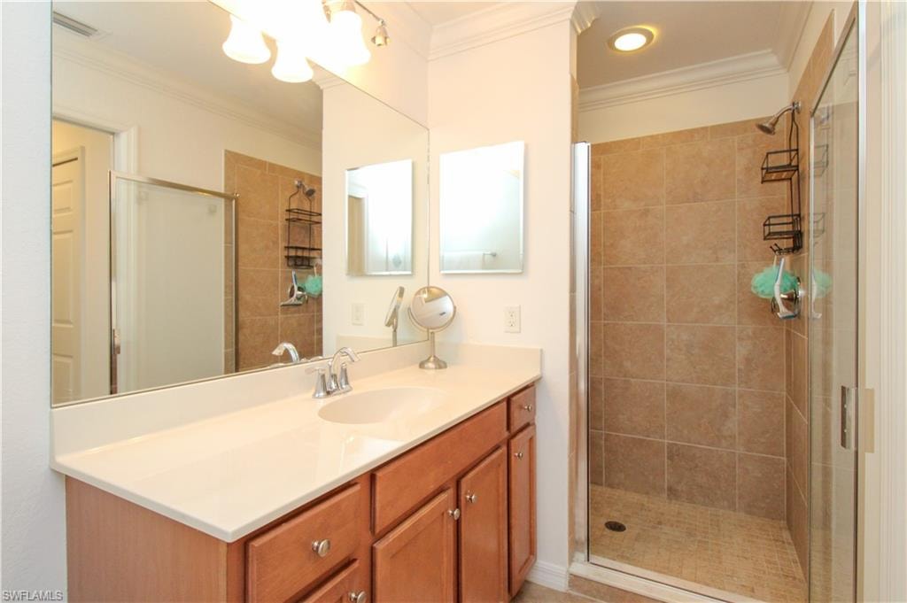 Bathroom featuring vanity, an enclosed shower, and crown molding