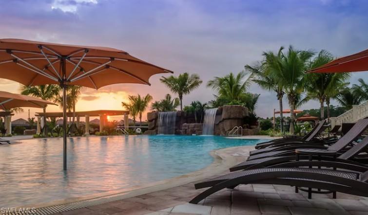 Pool at dusk featuring a patio area and pool water feature