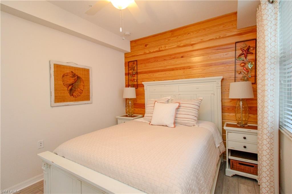 Bedroom with hardwood / wood-style floors, ceiling fan, and wooden walls