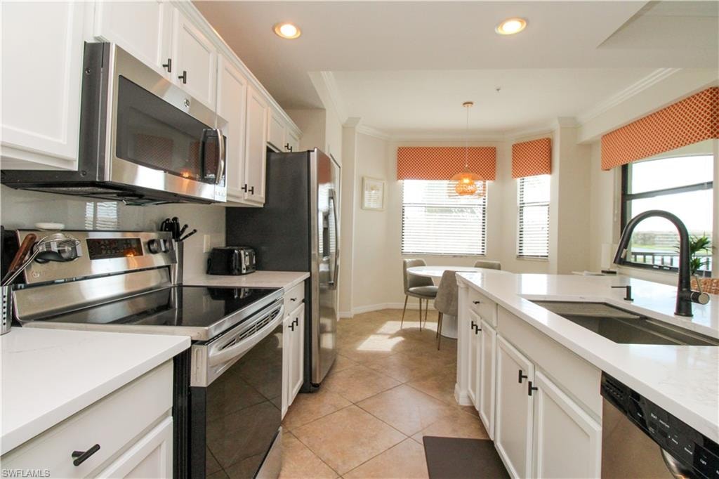 Kitchen featuring pendant lighting, white cabinets, sink, light tile patterned floors, and appliances with stainless steel finishes