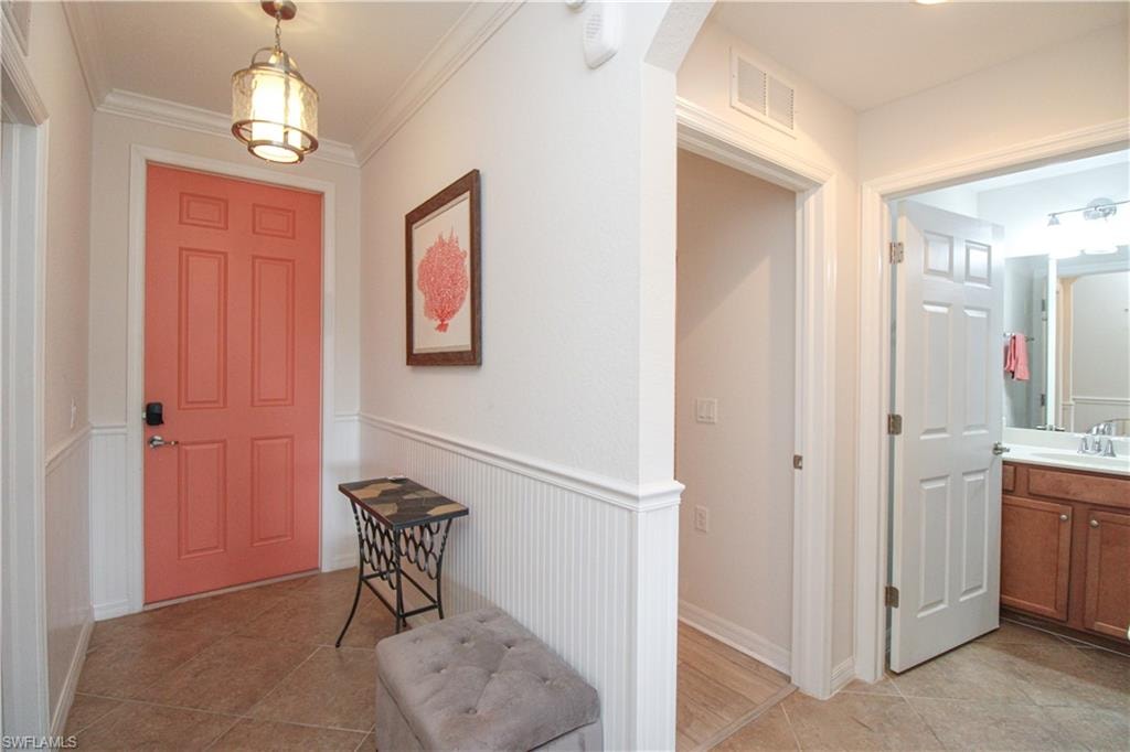 Tiled foyer entrance with sink and ornamental molding