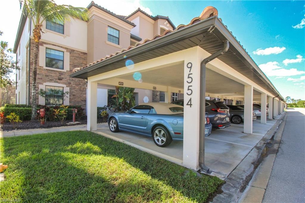 View of vehicle parking with a yard and a carport