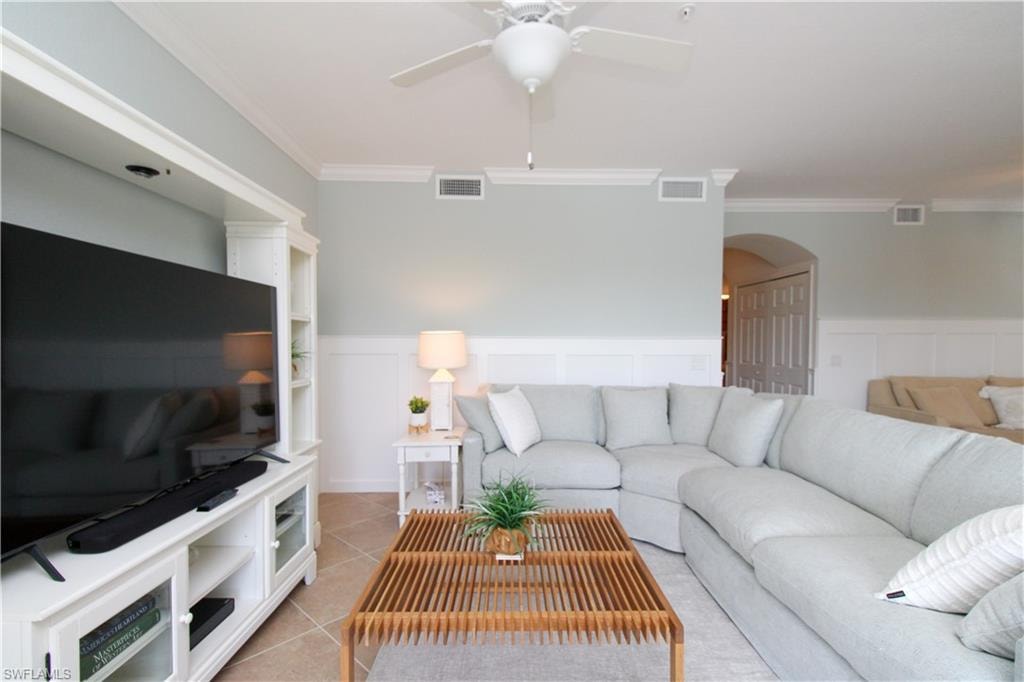 Living room with ceiling fan, light tile patterned floors, and ornamental molding