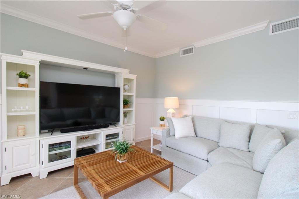 Tiled living room featuring ceiling fan and ornamental molding
