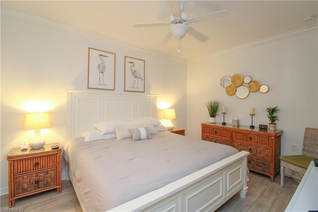 Bedroom with light wood-type flooring, ceiling fan, and ornamental molding