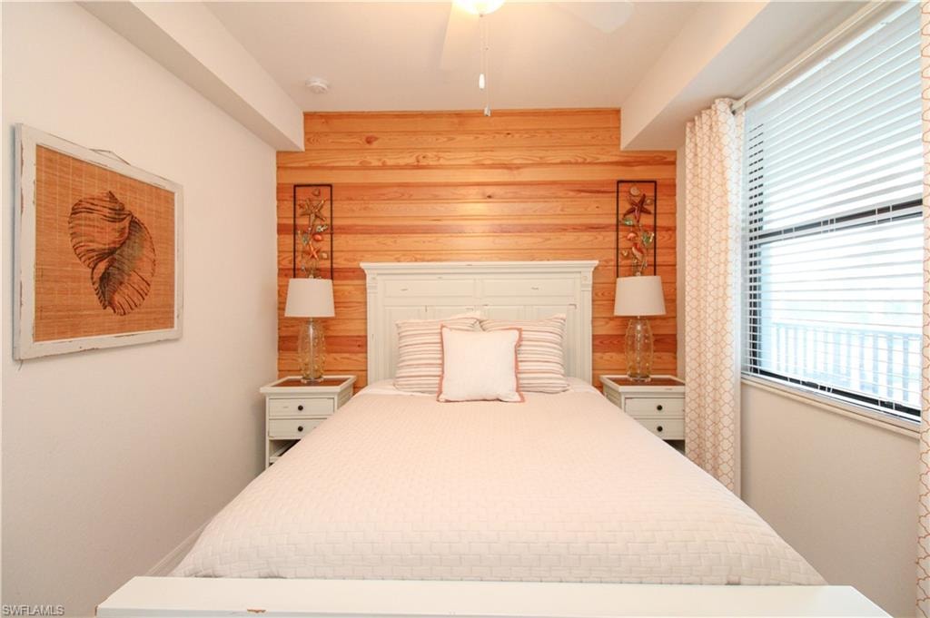 Bedroom with ceiling fan and wooden walls