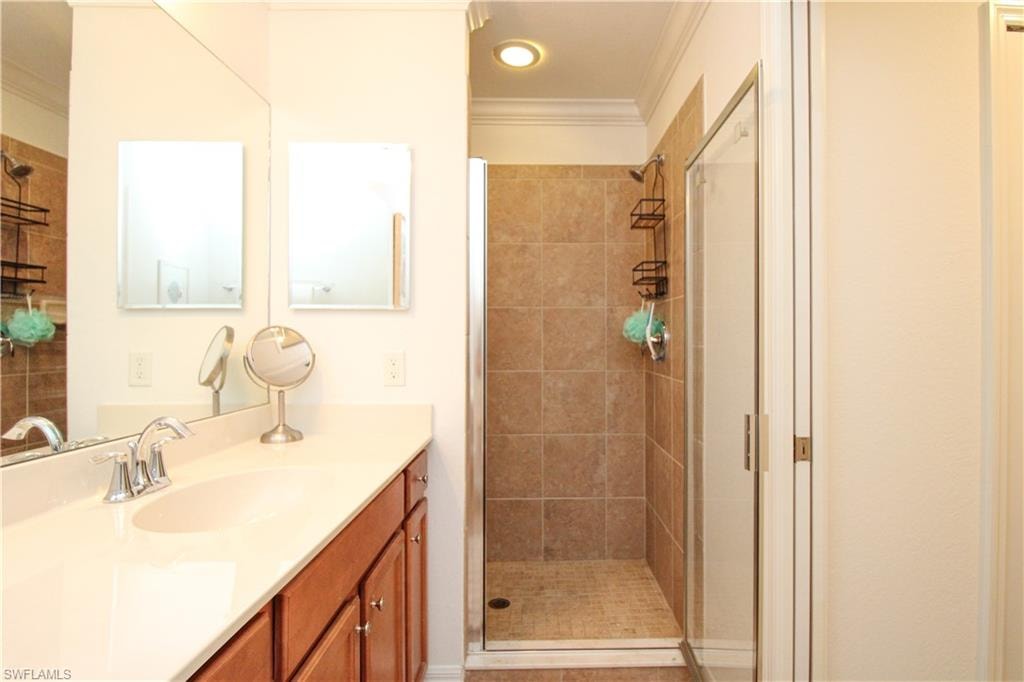 Bathroom with vanity, an enclosed shower, and ornamental molding