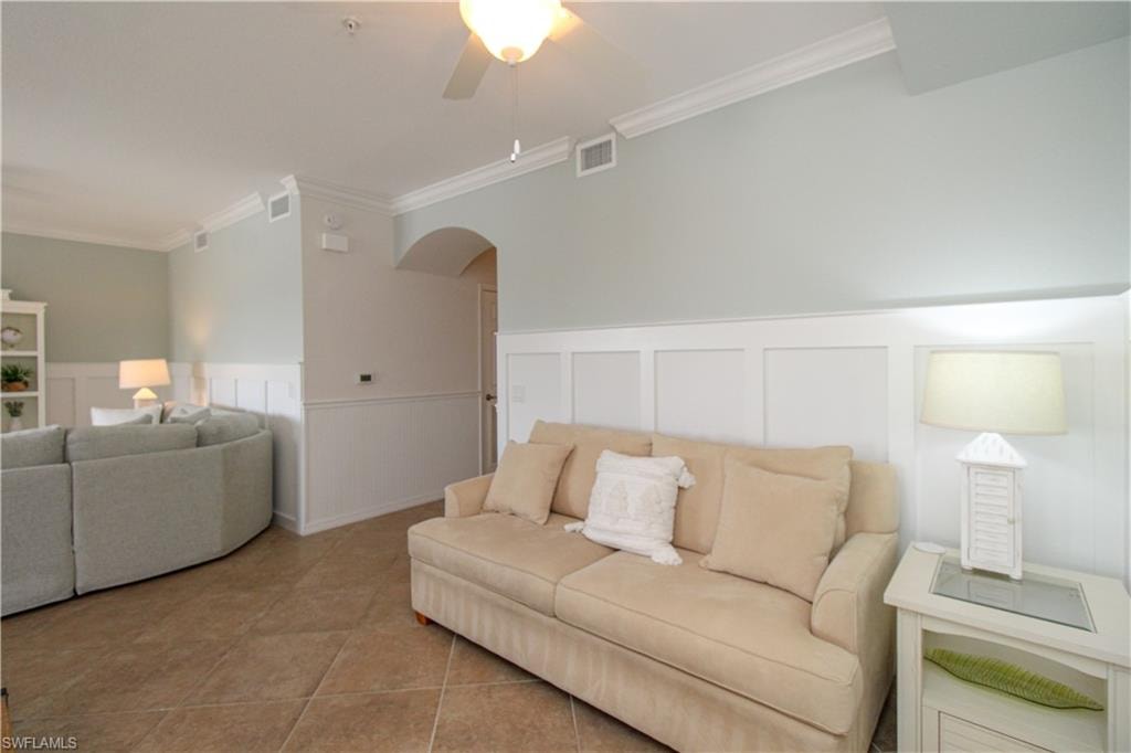 Tiled living room featuring ceiling fan and crown molding