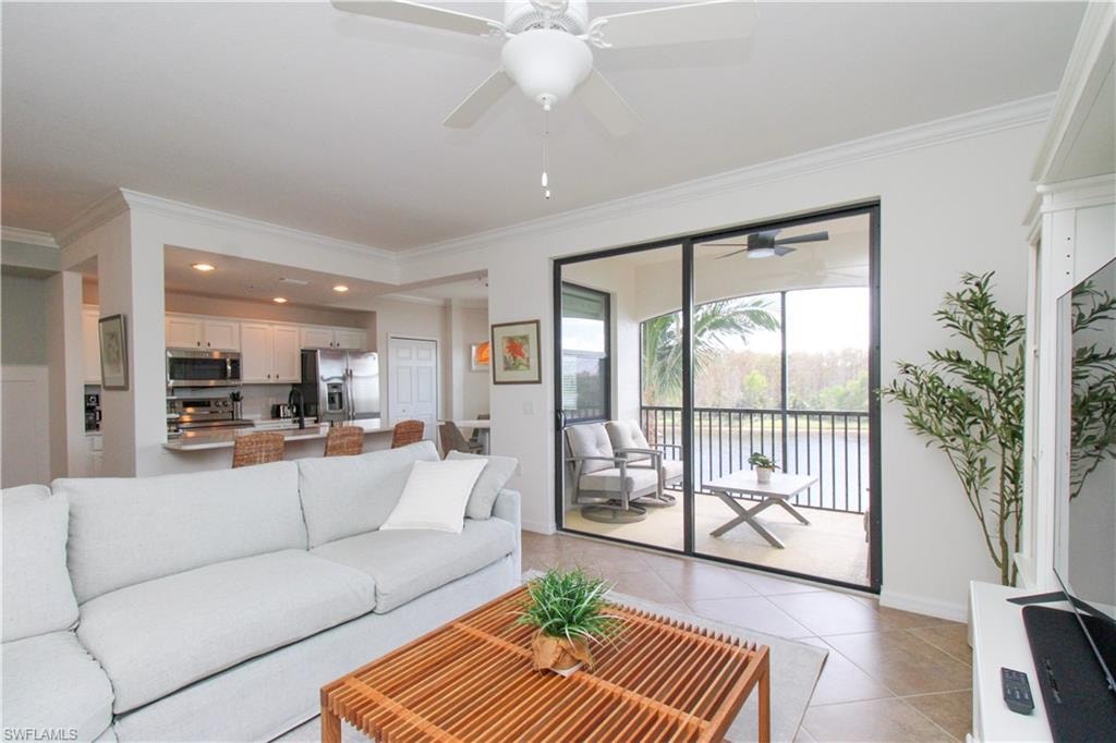 Living room featuring light tile patterned floors, ceiling fan, crown molding, and sink