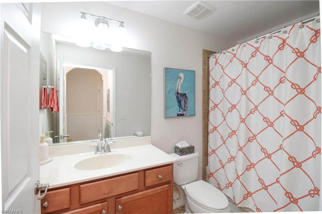 Bathroom featuring vanity, toilet, and curtained shower