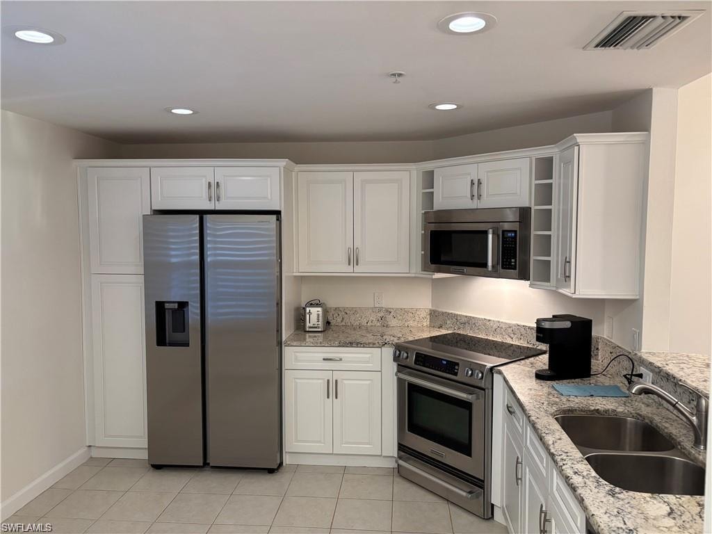Kitchen featuring stainless steel appliances, light stone counters, white cabinets, recessed lighting, and open shelves