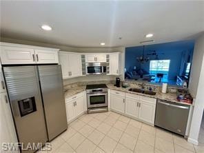 Kitchen with appliances with stainless steel finishes, white cabinetry, light countertops, light tile patterned floors, and recessed lighting