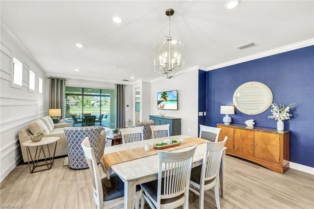 Dining space with recessed lighting, light wood-style flooring, crown molding, and a chandelier