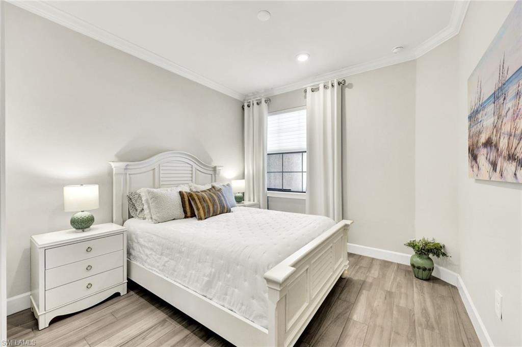 Bedroom with light wood finished floors and crown molding