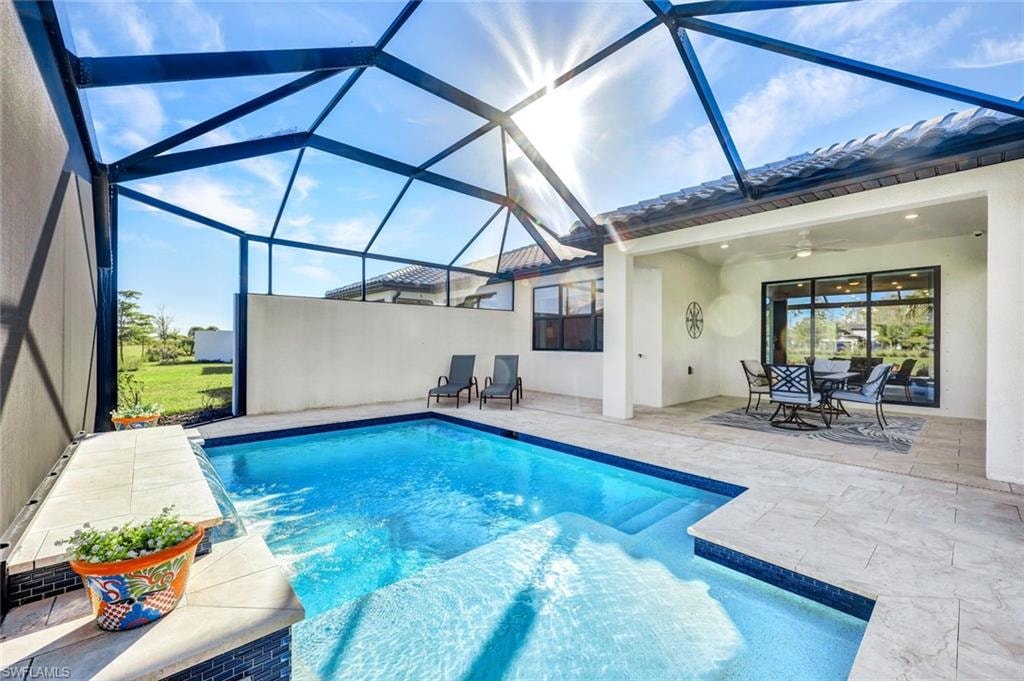 Swimming pool with a sunroom, a patio area, and glass enclosure