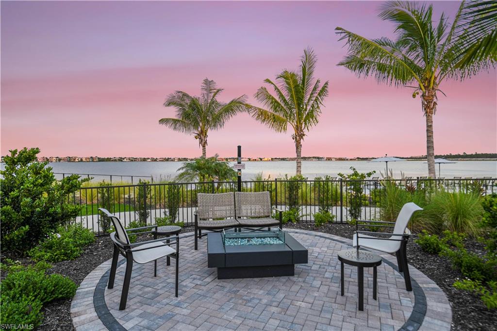 Fenced backyard featuring a patio area, a water view, and an outdoor living space with a fire pit