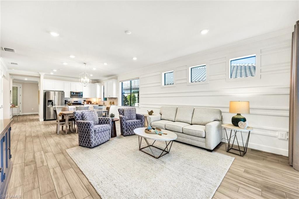 Living area featuring wood tiled floors, recessed lighting, crown molding, and a chandelier
