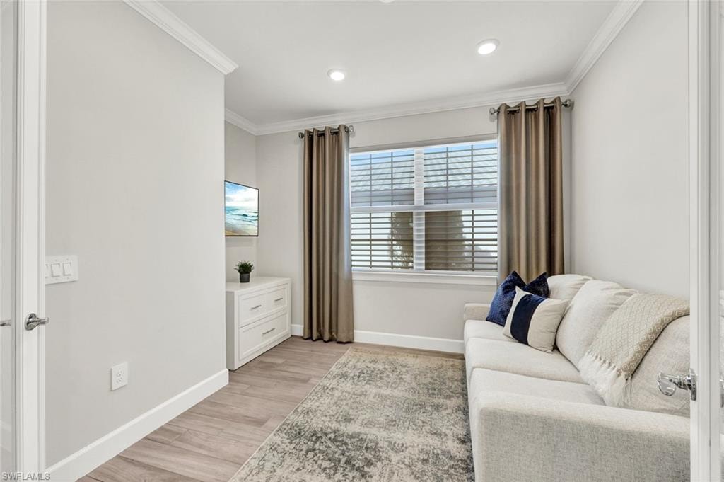 Sitting room with light wood-type flooring, ornamental molding, and recessed lighting