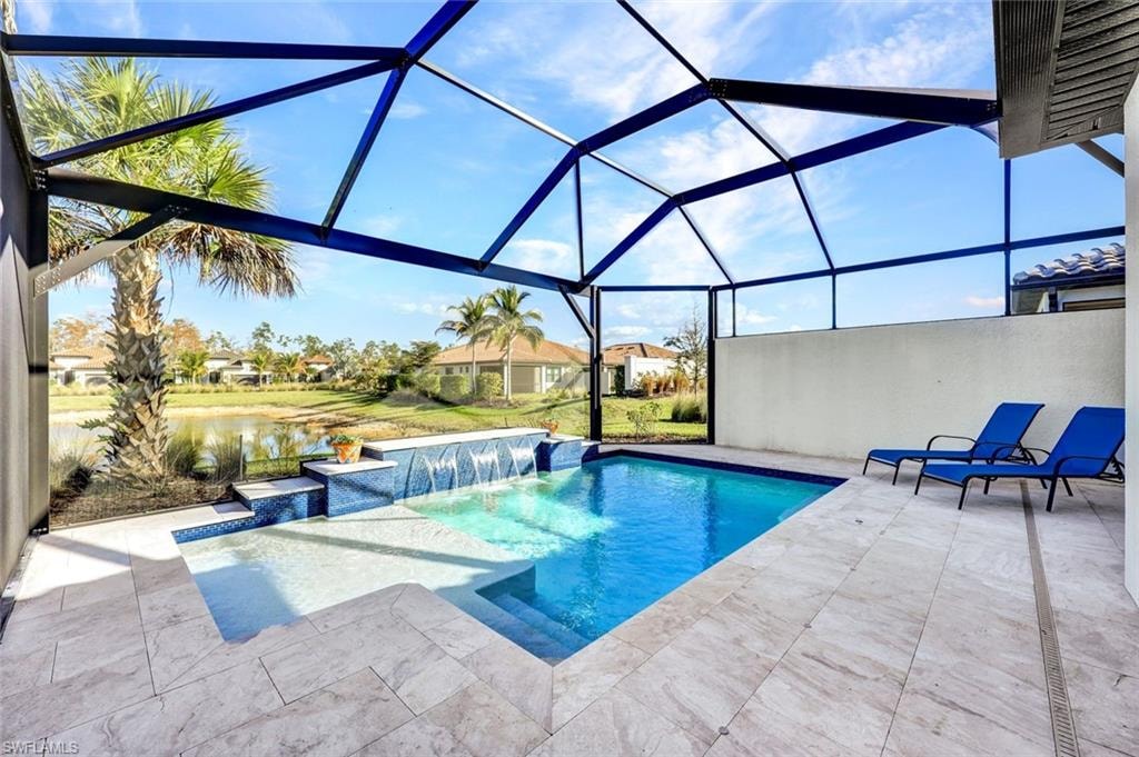 Swimming pool featuring a sunroom, glass enclosure, a water view, and a patio