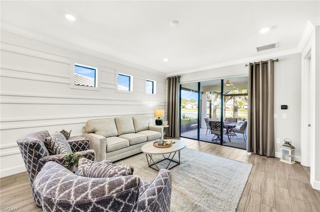 Living area featuring light wood-style flooring, healthy amount of natural light, ornamental molding, and recessed lighting