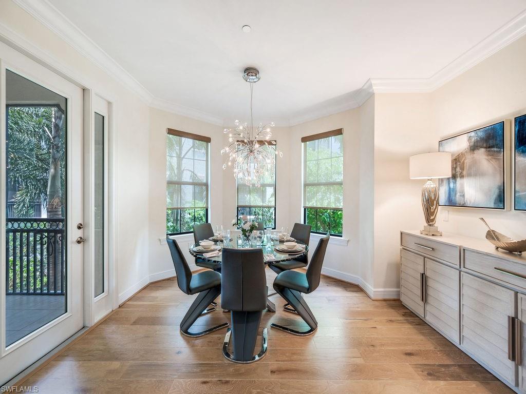 Dining space with ornamental molding, light wood-style flooring, and a chandelier