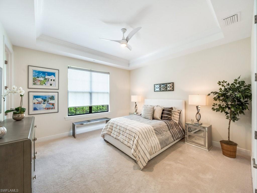 Bedroom with a raised ceiling, carpet floors, and a ceiling fan