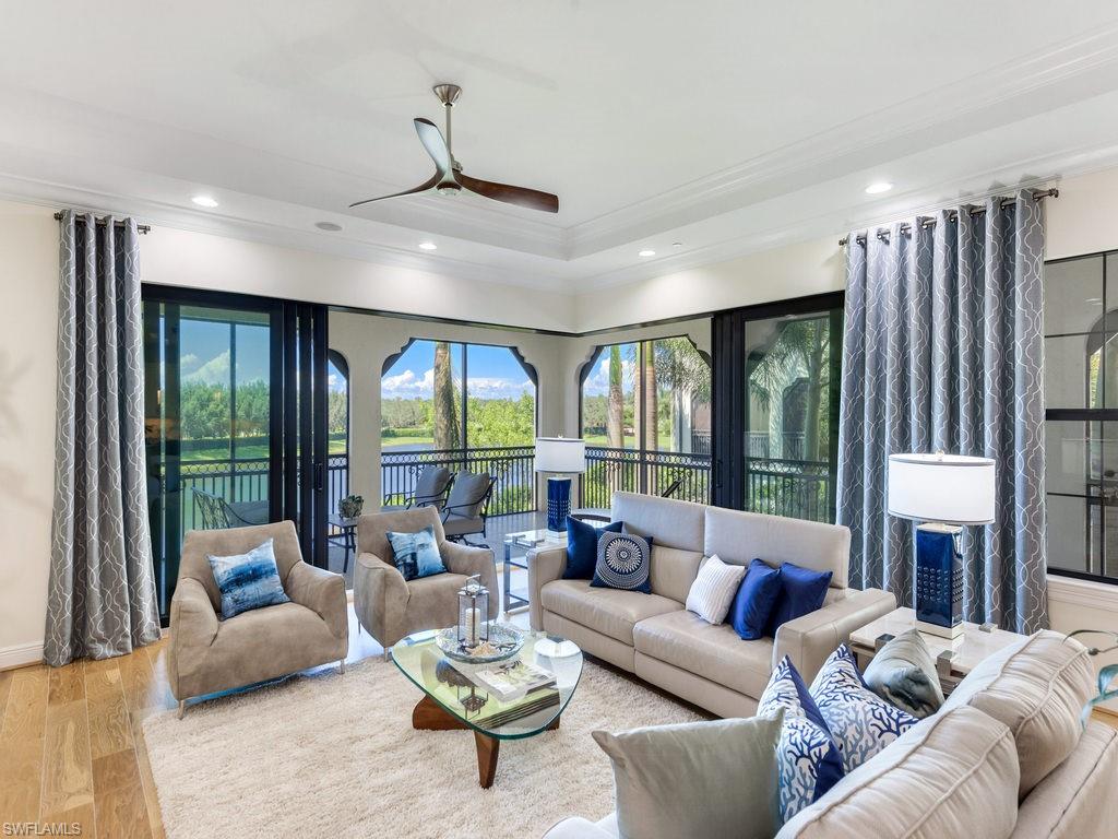 Living room featuring wood finished floors, ceiling fan, recessed lighting, crown molding, and a tray ceiling