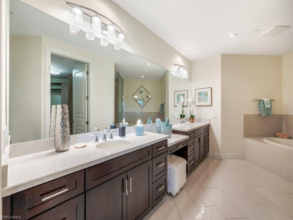 Bathroom featuring double vanity, light tile patterned flooring, a garden tub, and recessed lighting