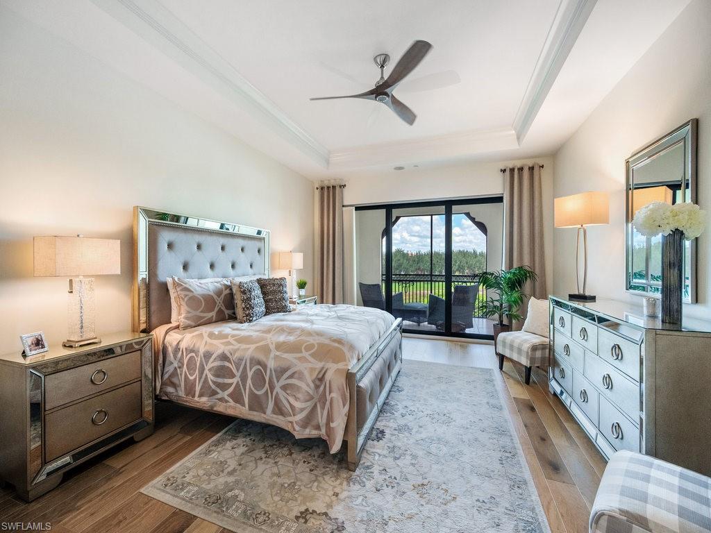Bedroom featuring access to outside, a raised ceiling, wood-type flooring, and a ceiling fan