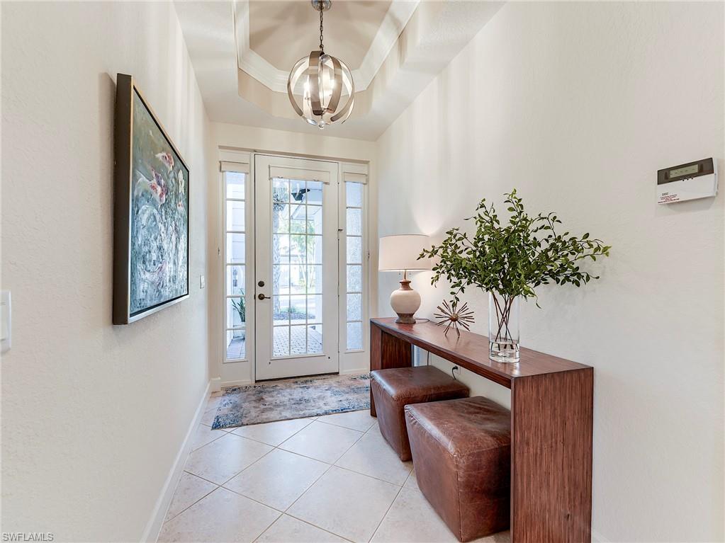 Entryway featuring light tile patterned floors, a tray ceiling, and a chandelier
