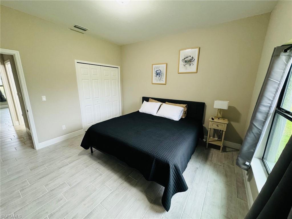 Bedroom with wood tiled floors, multiple windows, and a closet