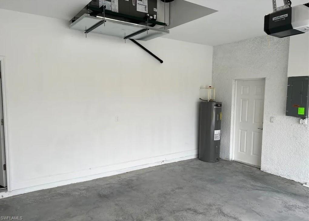 Garage featuring a garage door opener, electric panel, and water heater