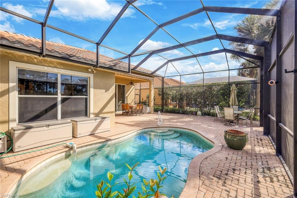 Outdoor pool with a sunroom, a patio area, a lanai, and outdoor dining space