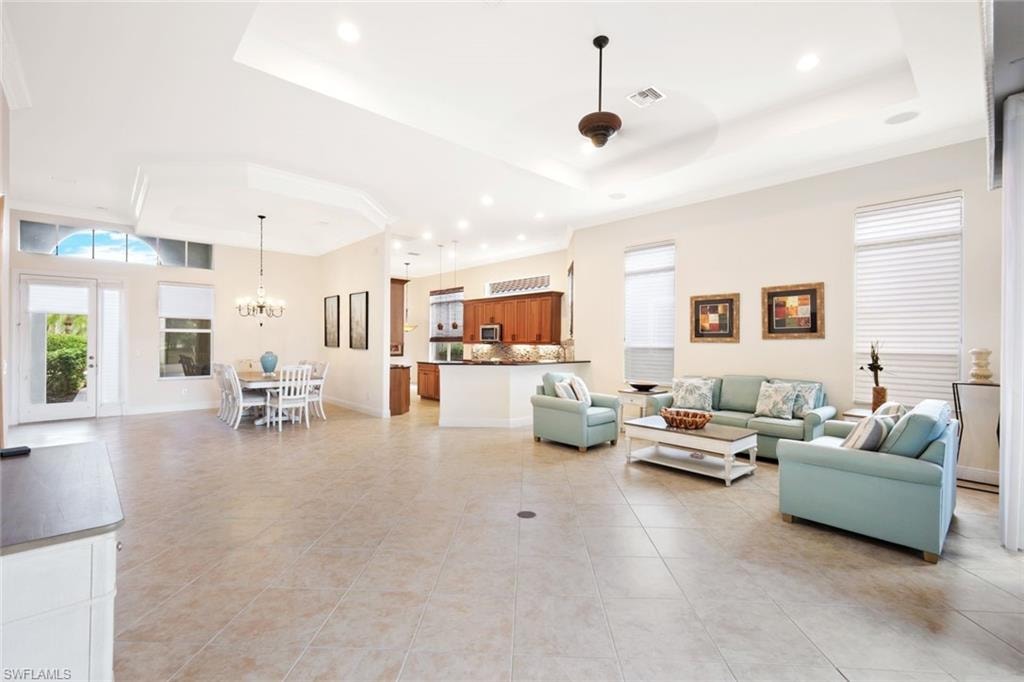Living area featuring recessed lighting, a raised ceiling, light tile patterned floors, and a chandelier