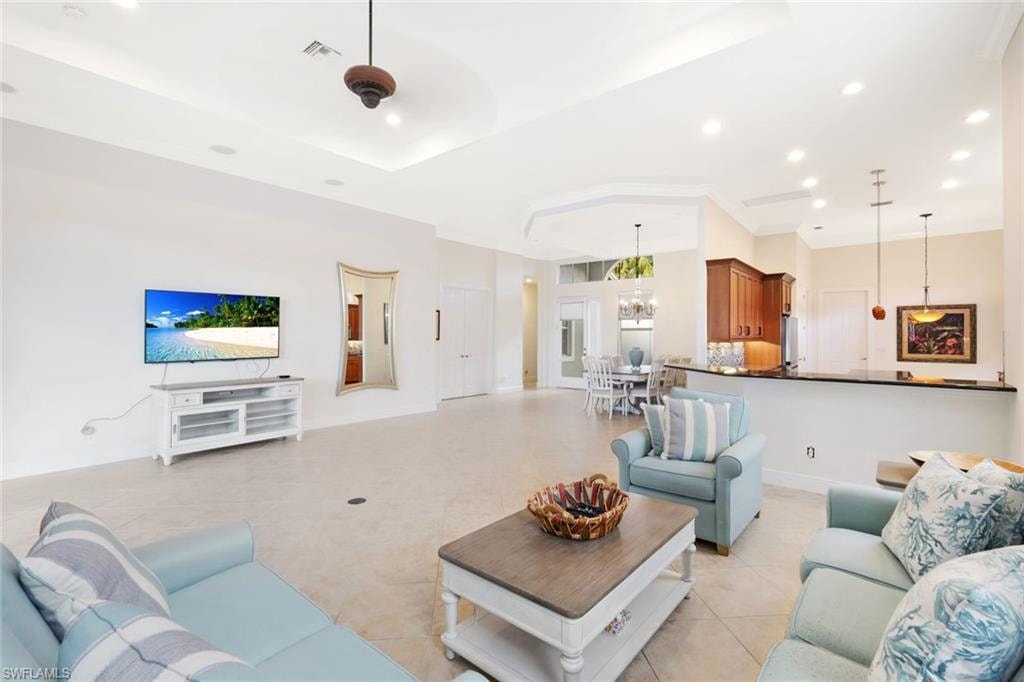 Living room with recessed lighting, light tile patterned floors, and a raised ceiling