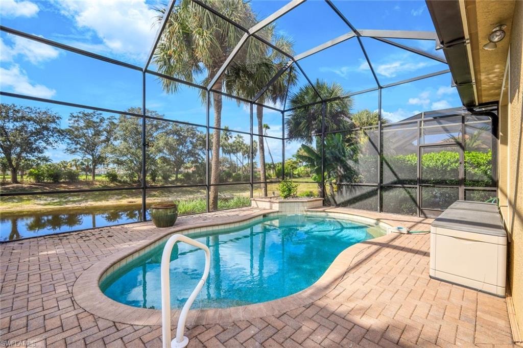 Outdoor pool with a sunroom, a patio, glass enclosure, and a water view
