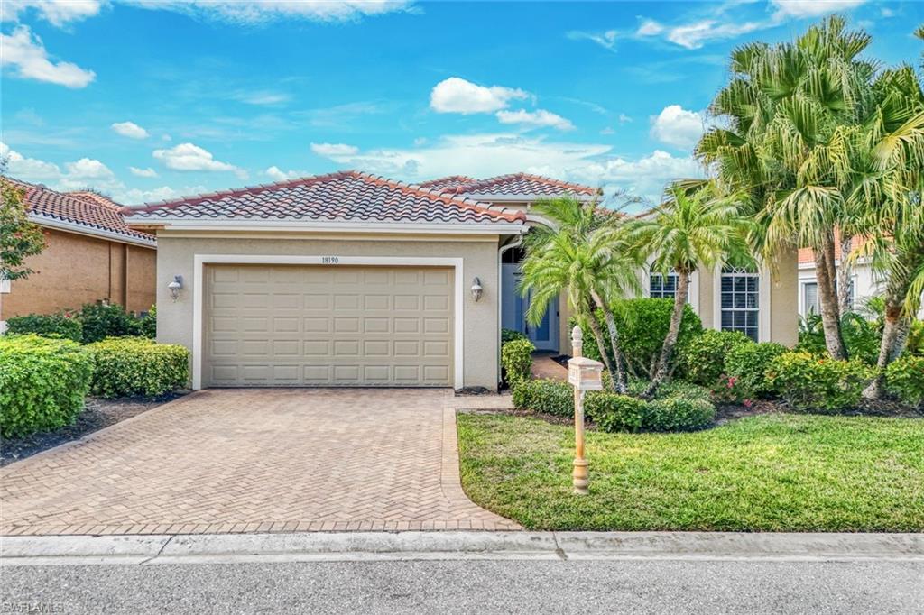 Mediterranean / spanish house with a front yard, stucco siding, decorative driveway, and a tiled roof