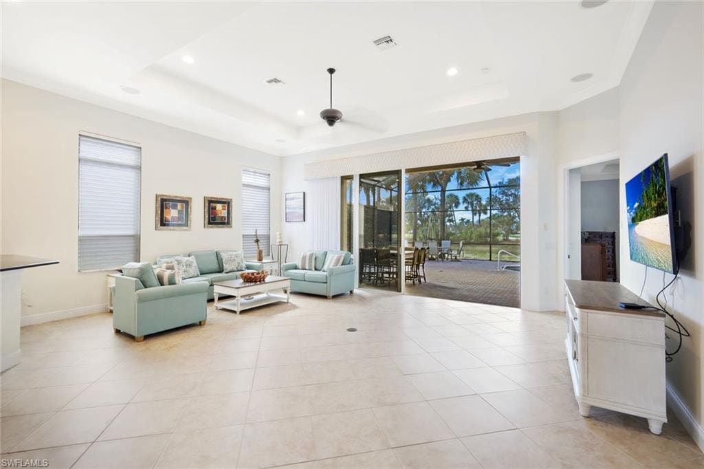 Living room featuring a sunroom, light tile patterned flooring, recessed lighting, ceiling fan, and a raised ceiling