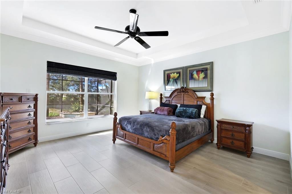 Bedroom featuring a raised ceiling, wood tiled floors, and a ceiling fan