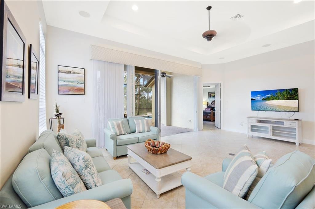Tiled living area featuring a tray ceiling, a ceiling fan, and recessed lighting