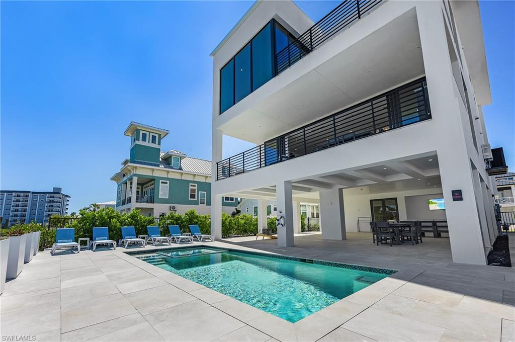 Rear view of house with a patio, a balcony, a pool with connected hot tub, and stucco siding - Virtually Edited Image